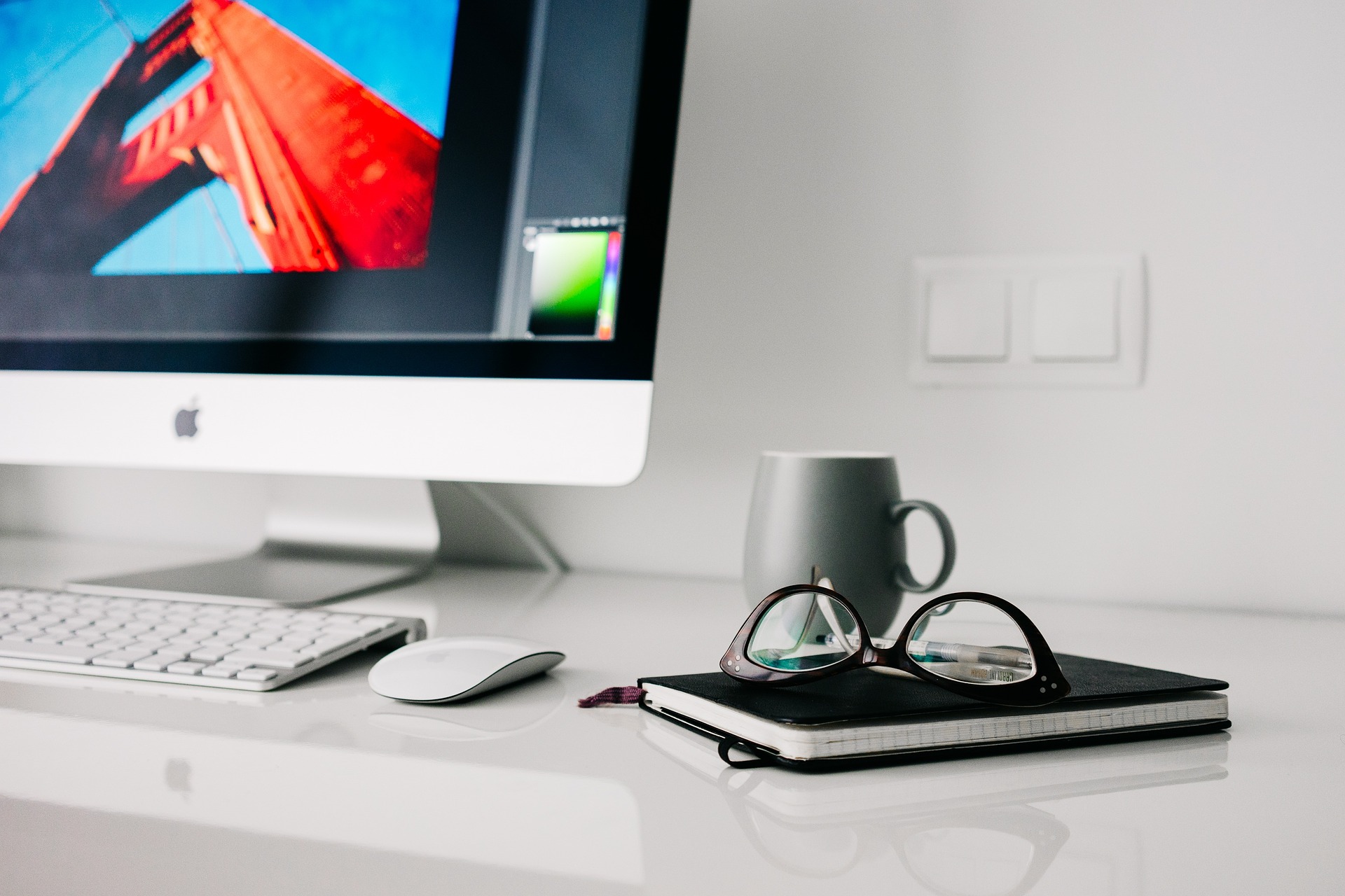 A desk with a computer and glasses